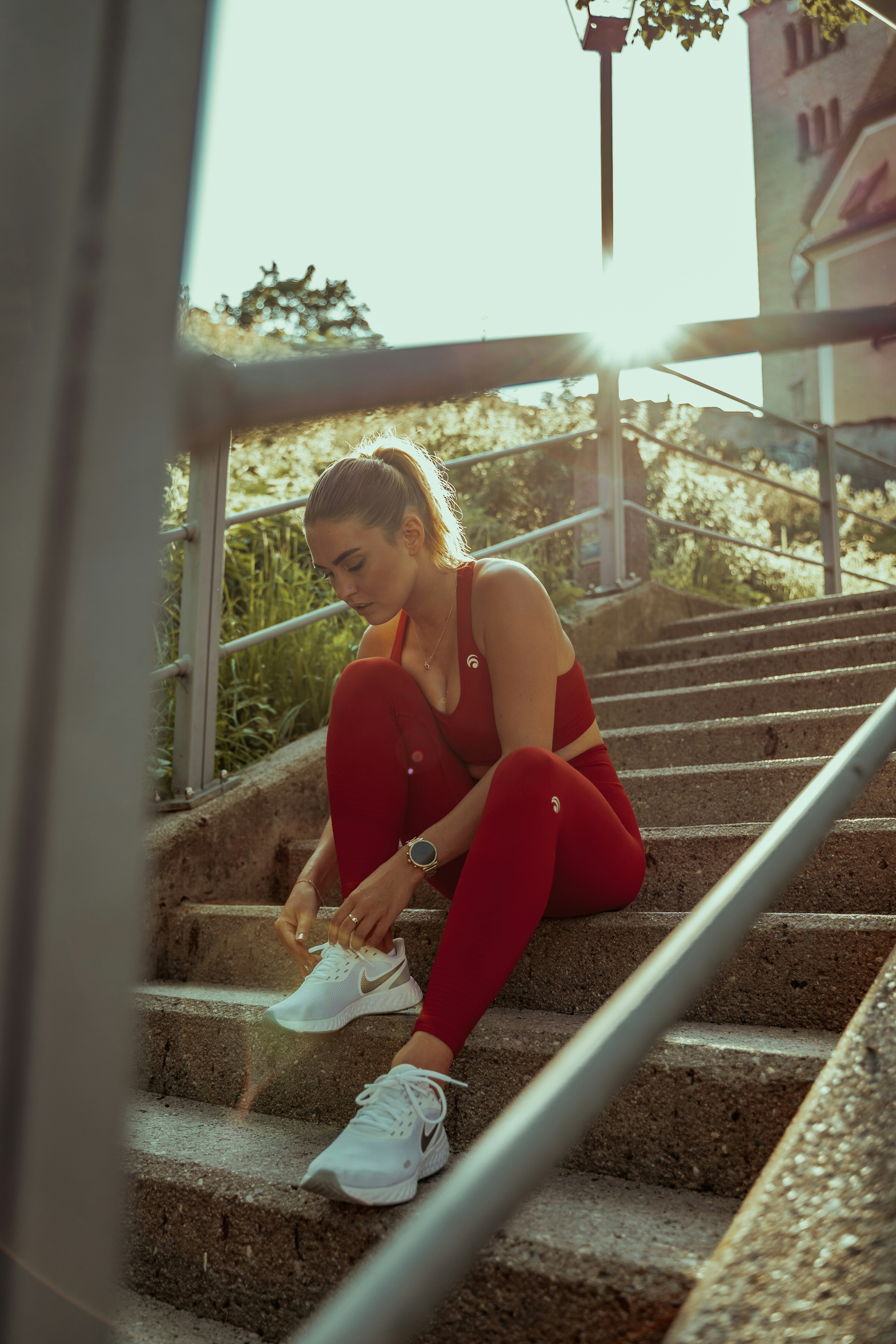 woman in red tank top sitting on white metal railings during daytime